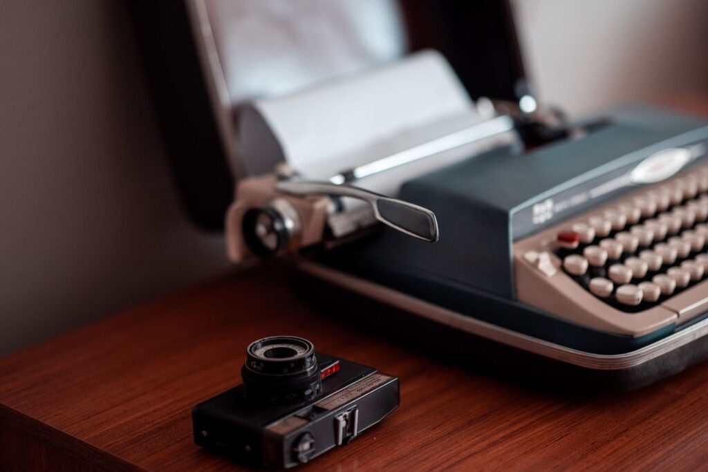 Typemachine, retrocamera en zonnebril op een houten tafel